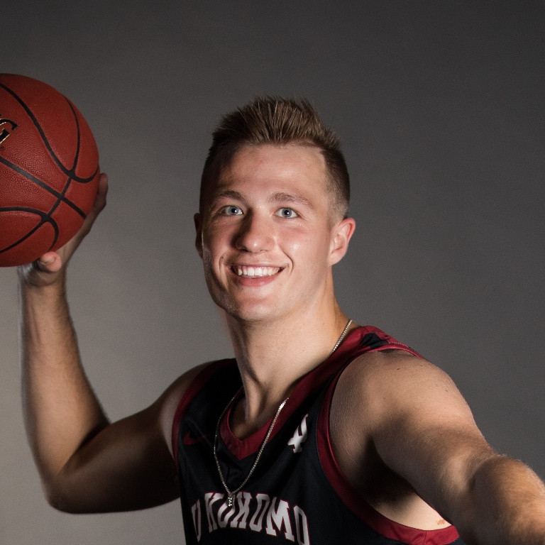 A male student holding a basketball.